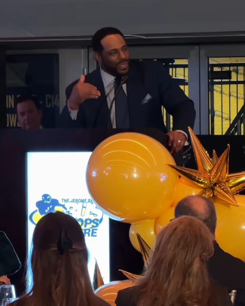Jerome Bettis speaking at the podium beside Party on Butler gold balloons